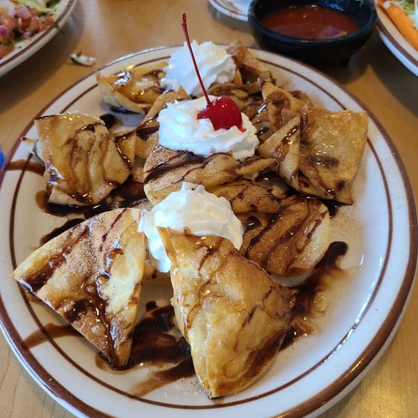 Fried tortilla dessert drizzled with chocolate, topped with whipped cream and a cherry at Jacky's Restaurant.