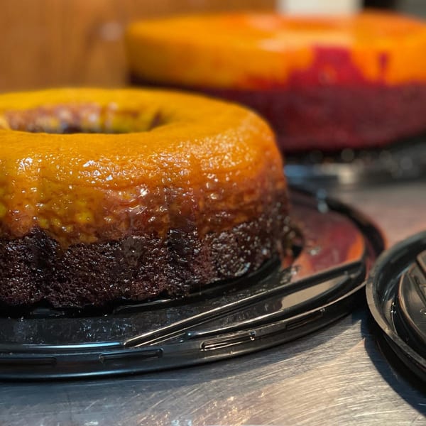 Two Mexican chocolate flan cakes with golden caramel topping on a metal counter.